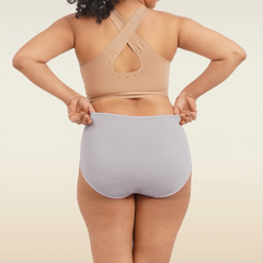 Person wearing a beige sports bra and light gray high-waisted underwear on a plain background