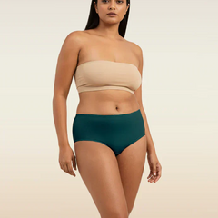 Woman wearing a beige strapless top and teal mid-waist underwear on a beige background
