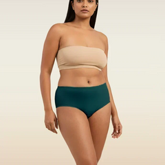 Woman wearing a beige strapless top and teal mid-waist underwear on a beige background