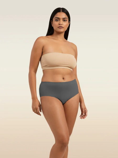 Woman wearing a beige strapless top and gray mid-waist underwear on a beige background
