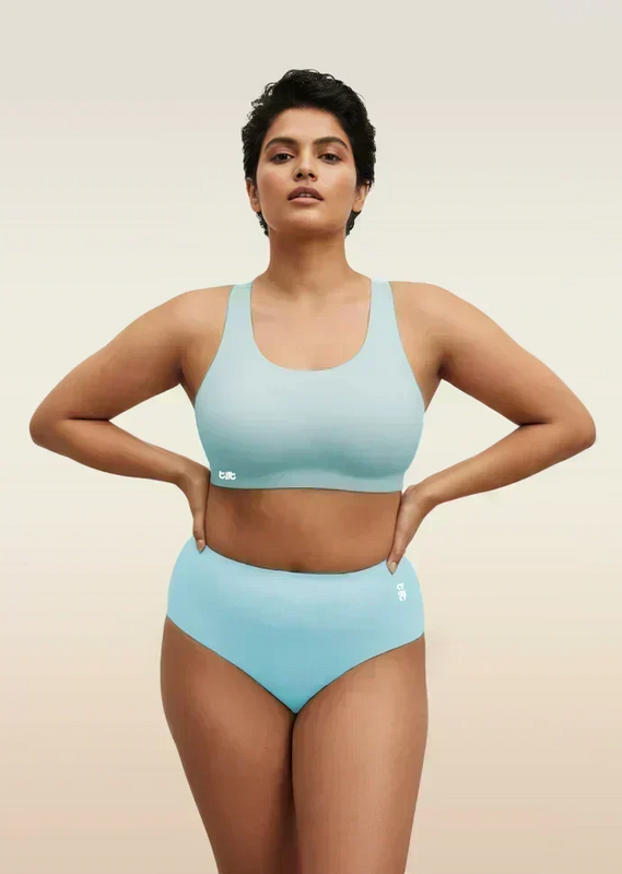 Woman wearing a blue bra and underwear set on a beige background