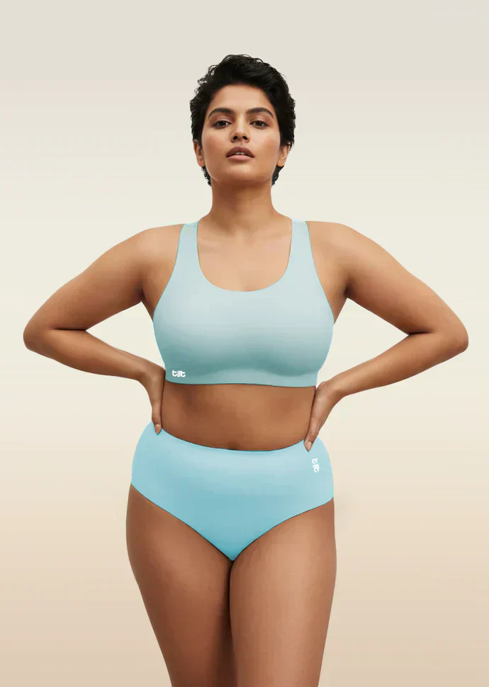 Woman wearing a blue bra and underwear set on a beige background