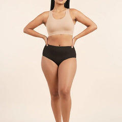 Woman wearing a beige sports bra and black mid-waist underwear on a beige background