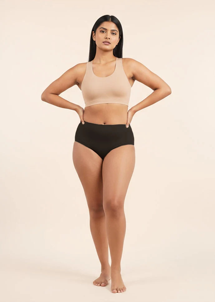 Woman wearing a beige sports bra and black mid-waist underwear on a beige background