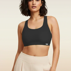 Woman wearing a black sports bra with a visible brand logo on a beige background