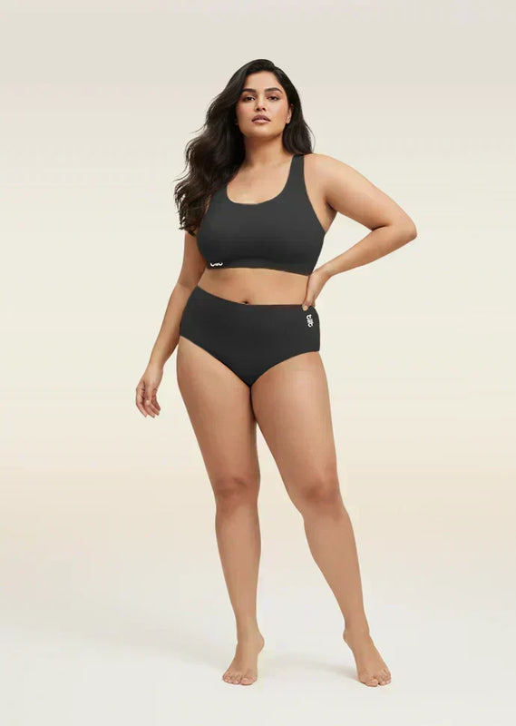 Woman wearing a black bra and  underwear set on a beige background