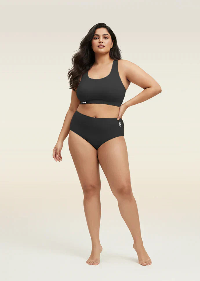 Woman wearing a black bra and  underwear set on a beige background