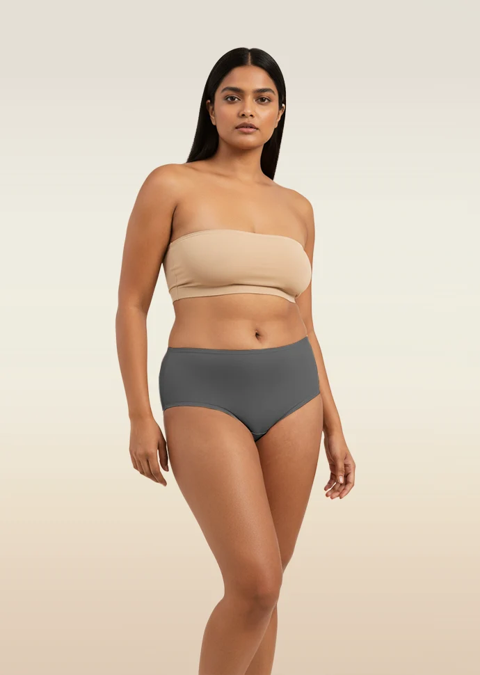 Woman wearing a beige strapless top and gray mid-waist underwear on a beige background
