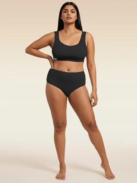 Woman wearing a black bra and underwear set on a beige background