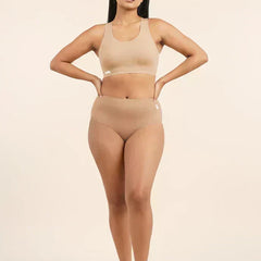 Woman wearing a beige sports bra and mid-waist underwear set on a beige background