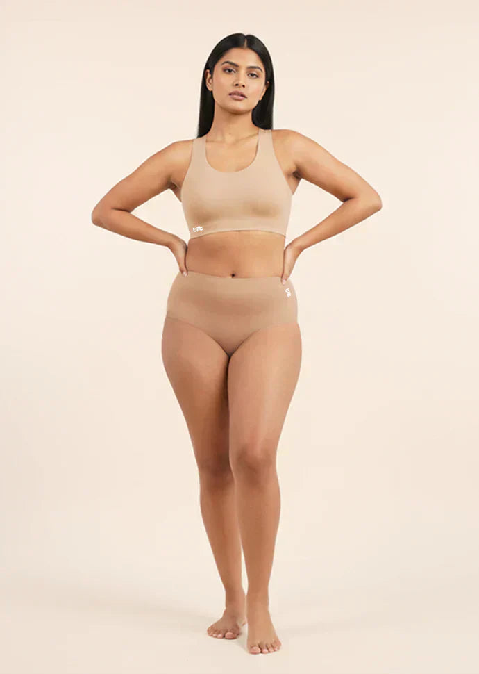 Woman wearing a beige sports bra and mid-waist underwear set on a beige background