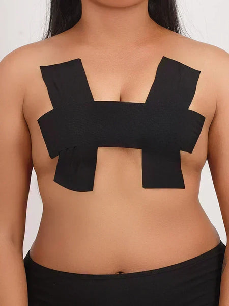 Front view of a person wearing black adhesive boob tape applied in a supportive H-pattern.