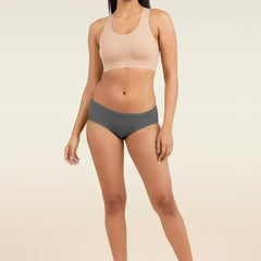 Woman wearing a beige sports bra and gray low-waist underwear on a beige background