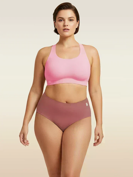 Woman wearing a pink sports bra and pink mid-waist underwear on a beige background