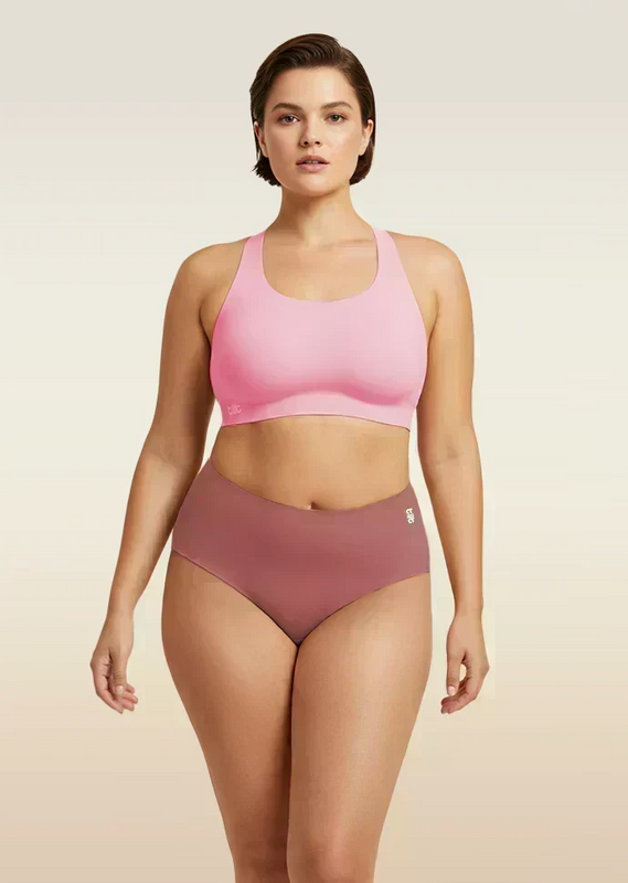 Woman wearing a pink sports bra and pink mid-waist underwear on a beige background