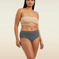 Woman wearing a beige strapless top and gray mid-waist underwear on a beige background