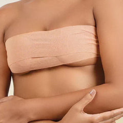 Woman wearing a beige boob tape  against a neutral background