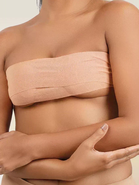 Woman wearing a beige boob tape  against a neutral background