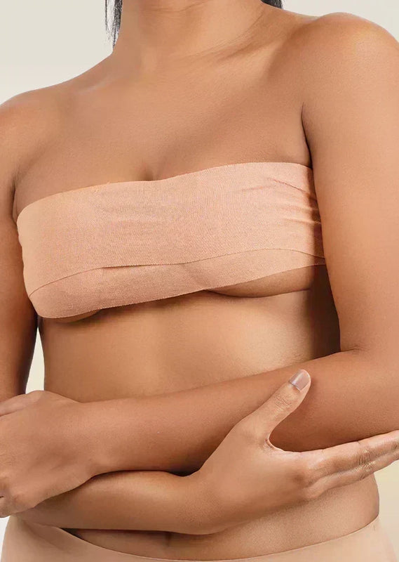 Woman wearing a beige boob tape  against a neutral background