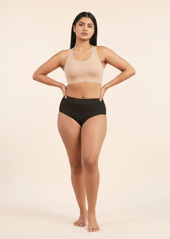 Woman wearing a beige sports bra and black mid-waist underwear on a beige background