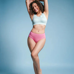 Woman wearing a light blue sports bra and pink mid-waist underwear against a blue background