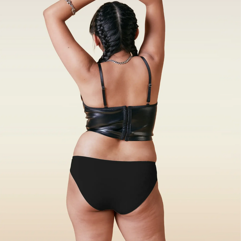 Person wearing a black leather outfit with gloves on a beige background