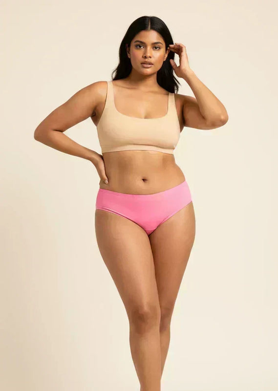Woman wearing a beige bikini top and pink low-waist underwear on a beige background