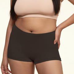Person wearing a beige sports bra and black boyshorts on a beige background