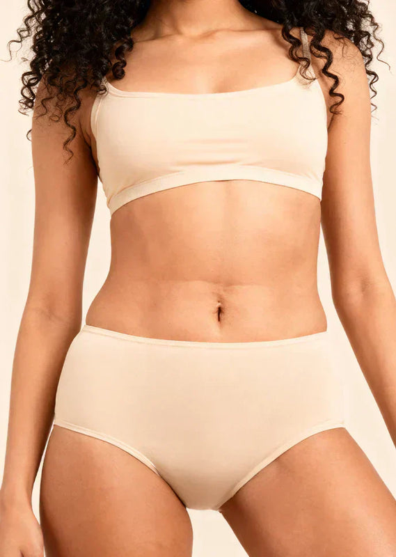 Person wearing a beige bra and underwear against a neutral background