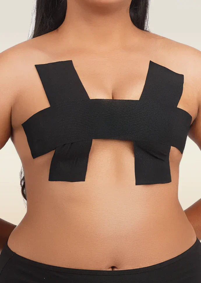 Front view of a person wearing black adhesive boob tape applied in a supportive H-pattern.