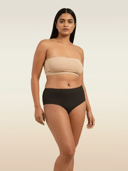Woman wearing a beige strapless bra and black underwear on a beige background