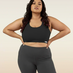 Woman wearing a black sports bra and leggings on a beige background