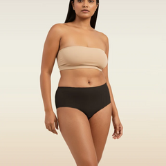 Woman wearing a beige strapless bra and black underwear on a beige background