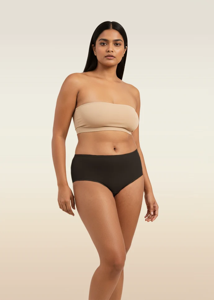 Woman wearing a beige strapless bra and black underwear on a beige background