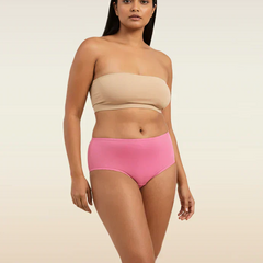 Woman wearing a beige strapless top and pink mid-waist underwear on a beige background
