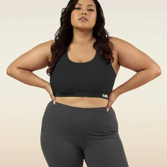 Woman wearing a black sports bra and leggings on a beige background