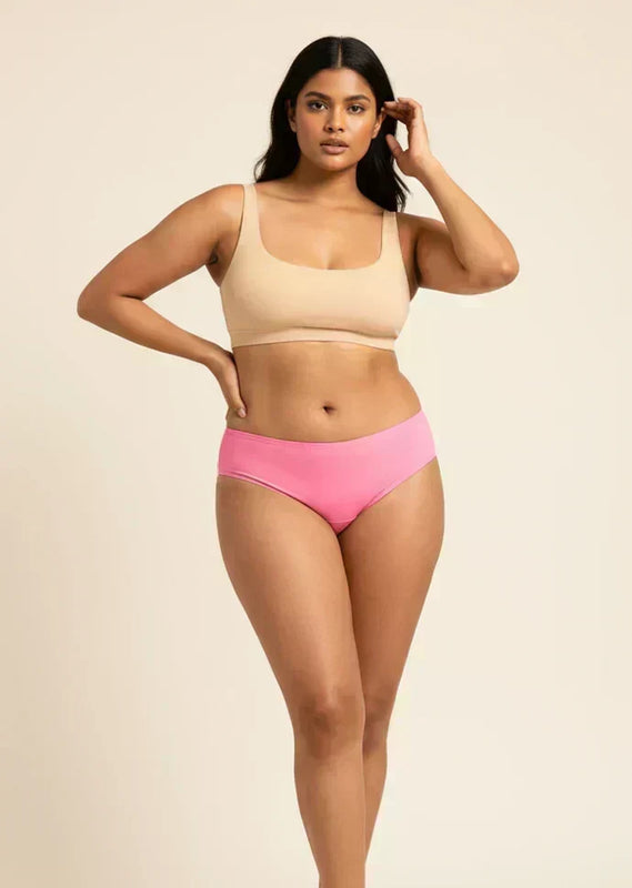 Woman wearing a beige bikini top and pink low-waist underwear on a beige background