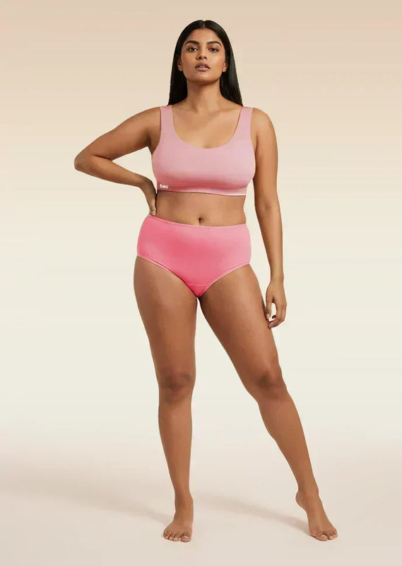 Woman wearing a pink bra and underwear set on a beige background