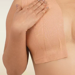 Person wearing a beige boob tape against a neutral background