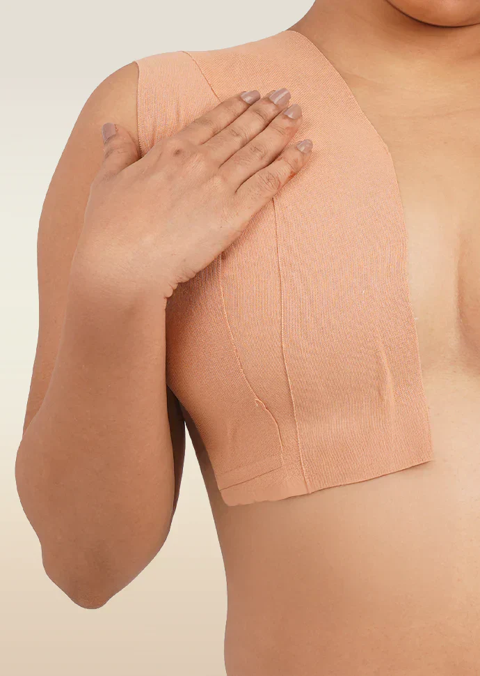 Person wearing a beige boob tape against a neutral background