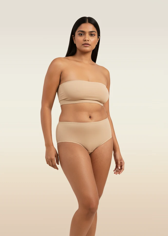 Woman wearing a beige strapless top and mid-waist underwear on a beige background