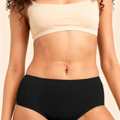 Person wearing a beige bra and black  underwear against a neutral background