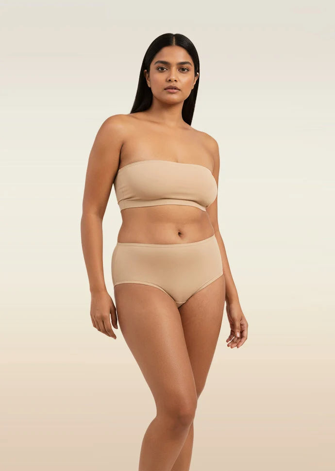 Woman wearing a beige strapless top and mid-waist underwear on a beige background