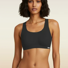 Woman wearing a black sports bra with a beige background