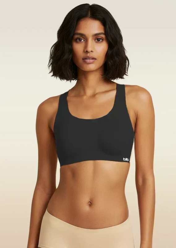 Woman wearing a black sports bra with a beige background