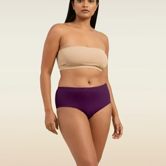 Woman wearing a beige strapless top and violet mid-waist underwear on a beige background