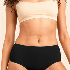 Person wearing a beige bra and black  underwear against a neutral background