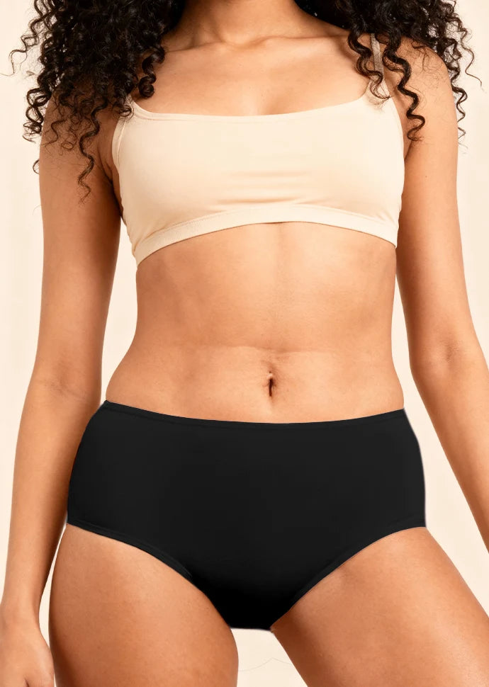 Person wearing a beige bra and black  underwear against a neutral background