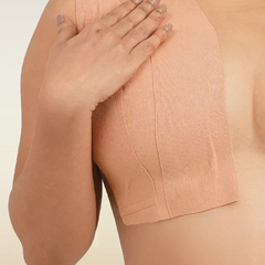 Person wearing a beige boob tape against a neutral background