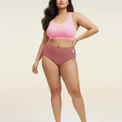 Woman wearing a pink sports bra and mid-waist underwear on a beige background